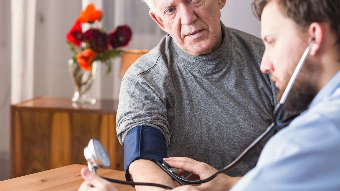 A healthcare professional monitoring a patient's blood pressure with a digital monitor.